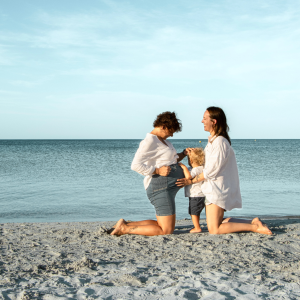 Maternity portrait of a woman at the beach, capturing the joy of pregnancy with the ocean waves in the background.