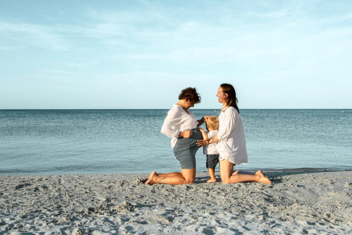 Maternity portrait of a woman at the beach, capturing the joy of pregnancy with the ocean waves in the background.