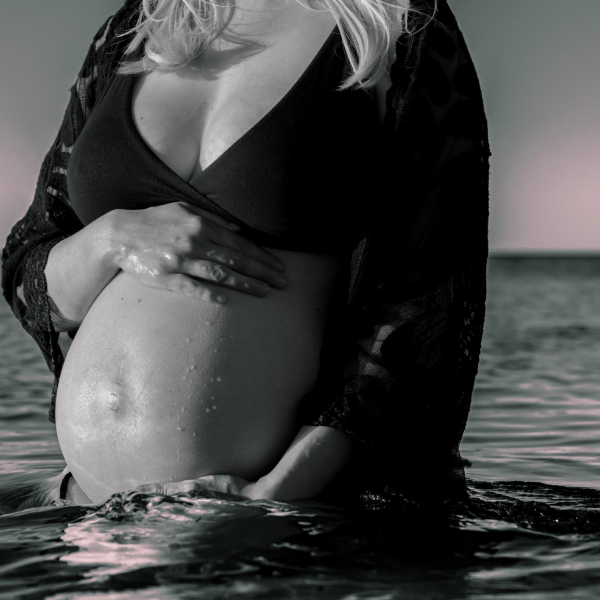 Maternity beach photoshoot featuring a glowing pregnant woman, surrounded by the tranquil beauty of the seaside.