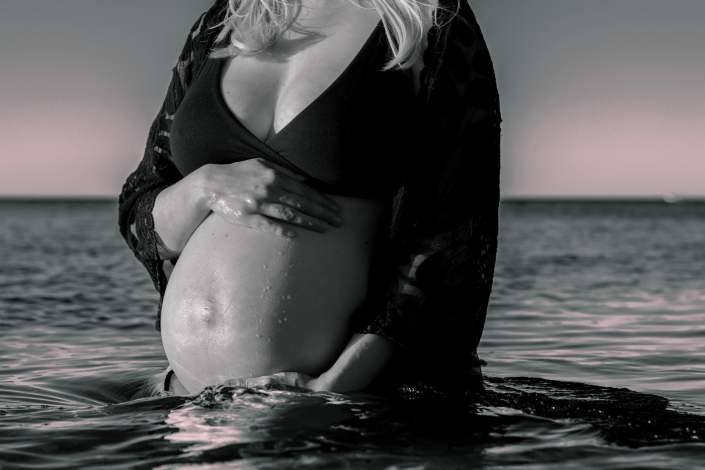 Maternity beach photoshoot featuring a glowing pregnant woman, surrounded by the tranquil beauty of the seaside.